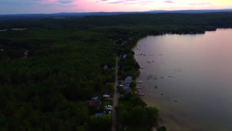 Beautiful-red-sunset-reflecting-off-the-water-near-the-shore,-drone-video