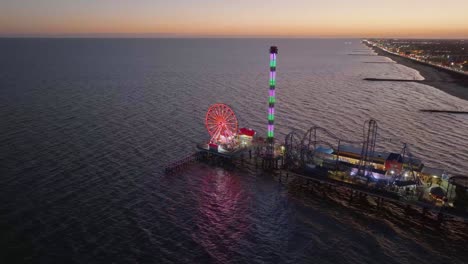 Aerial-view-towards-the-Illuminated-Texas-Flyer-and-the-Ferris-wheel-at-the-Galveston-Island-Historic-Pleasure-Pier