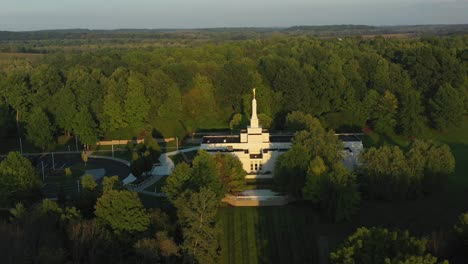 Pull-back-drone-shot-of-the-Palmyra-temple-near-the-Joseph-Smith-family-farm,-frame-house,-visitors-center,-sacred-grove-in-Palmyra-New-York-Origin-locations-for-the-Mormons-and-the-book-of-Mormon