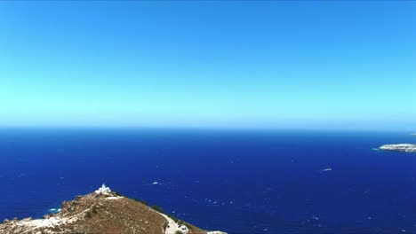 Vista-Aérea-4k-Azul-Mar-Y-Cielo-Sobre-El-Faro-Akrotiri-Hacia-La-Costa-En-Santorini-Grecia