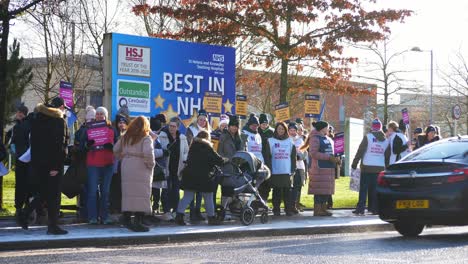 NHS-nurses-strike-for-fair-pay-and-better-care-at-St-Helens-hospital-on-a-chilly-winter-morning,-waving-banners-and-flags