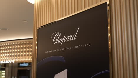 Inside-luxurious-Barcelona-jewellery-store-with-elegant-gold-Chopard-brand-advertisement-on-wall