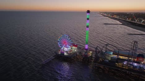 Bunte-Abendlichter-Am-Historischen-Pleasure-Pier-Von-Galveston-Island---Luftaufnahme