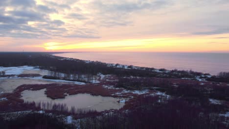 Swampy-coast-in-winter-aerial-view-with-colorful-sunset-at-the-horizon