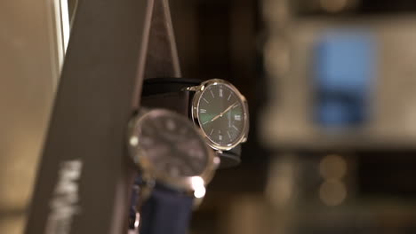 VERTICAL-Close-up-on-luxury-Baume-Mercier-stylish-watches-shining-on-display-in-jewellery-store-glass-counter