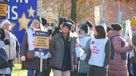 NHS-nurses-strike-protest-for-fair-pay-and-better-care-outside-St-Helens-hospital-on-a-chilly-winter-morning,-waving-banners-and-flags