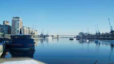 Panning-shot-of-London-Royal-Docks,-showing-the-beautiful,-peaceful-water,-on-a-quite-winter's-morning