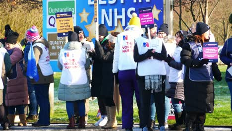 UK-hospital-nurses-protest-picket-line-for-fair-pay,-holding-banners-and-flags-on-strike