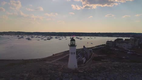 Lighthouse-with-an-American-flag,-Harbor-with-lots-of-boats