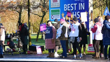 Enfermeras-Del-Nhs-En-Huelga-Por-Un-Salario-Justo-Y-Una-Mejor-Atención-Fuera-Del-Hospital-St-Helens-En-Una-Fría-Mañana-De-Invierno,-Ondeando-Pancartas-Y-Banderas