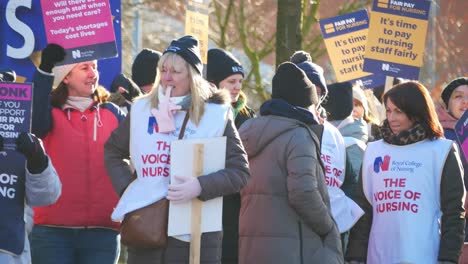 NHS-nurses-strike-for-fair-pay-and-better-care-outside-UK-hospital-on-a-chilly-winter-morning,-waving-banners-and-flags