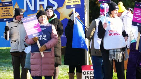 NHS-nurses-strike-for-fair-pay,-waving-banners-and-flags-outside-UK-Merseyside-hospital