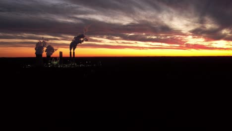 Aerial-4K-Time-Lapse-of-colorful-red-and-orange-sun-setting-behind-power-plant-cooling-towers-at-Miller-Power-Plant-in-West-Jefferson,-Alabama