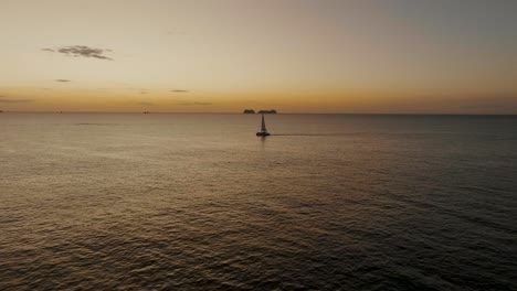 Sailboat-On-The-Ocean-At-Sunset-In-Guanacaste,-Costa-Rica---aerial-drone-shot