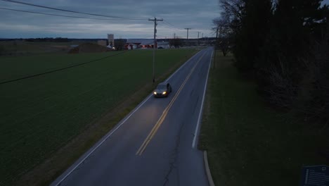 Descending-aerial-tracking-shot-of-new-Audi-sedan-driving-on-rural-road-in-America-at-night