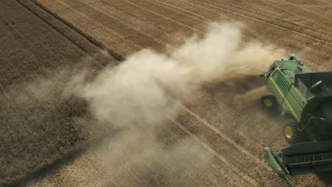 Drone-Shot-of-Green-John-Deere-Combine-Harvester-Turning-at-the-End-of-Field-with-Dust-on-Sunny-Day-UK