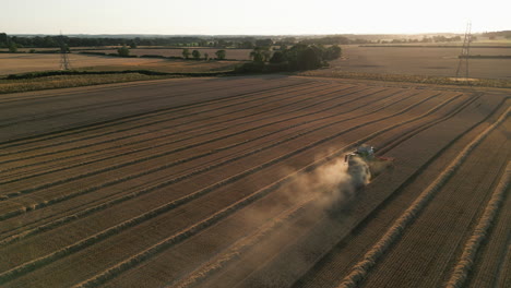 Establishing-Drone-Shot-of-Back-of-Claas-Combine-Harvester-with-Dust-Harvesting-into-Golden-Hour-Sunset-UK