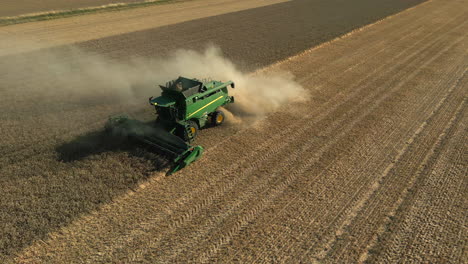 Rotating-Drone-Shot-of-Green-John-Deere-Combine-Harvester-Harvesting-with-lots-of-Dust-on-Sunny-Day