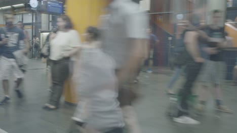 POV-from-inside-a-subway-arriving-at-a-yellow-subwaystation-in-Munich,-Germany,-while-people-are-waiting-for-it-to-arrive