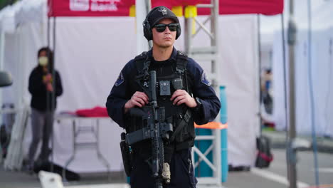 Un-Oficial-De-Policía-Con-Un-Rifle-De-Asalto-Hace-Guardia-Afuera-De-Las-Carpas-De-Los-Vendedores-Después-Del-Tiroteo-En-El-Parque-De-Monterey-Durante-El-Año-Nuevo-Lunar