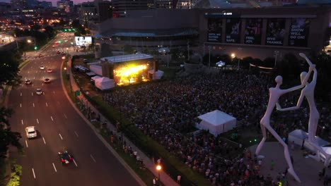 Vuelo-De-Drones-Sobre-Speer-Boulevard-Y-Multitud-En-Concierto-Nocturno---Parque-De-Esculturas,-Complejo-De-Artes-Escénicas,-Centro-De-Denver,-Colorado