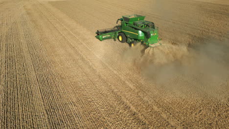 Low-Drone-Shot-of-Green-John-Deere-Tractor-Harvesting-with-Dust-on-Sunny-Day-UK