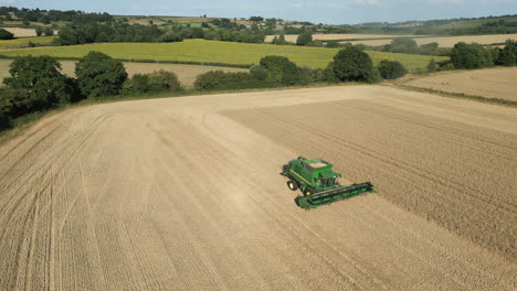 Establishing-Drone-Shot-of-Full-Green-John-Deere-Combine-Harvester-Driving-Down-Field-UK