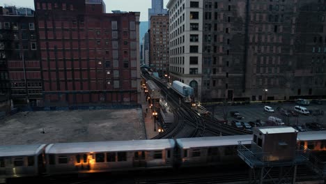 Elevated-Subway-Train-Passing-Through-City-Center-At-Dusk-Drone