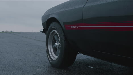 Ford-Mustang-Mach-1-En-Camino-Húmedo-En-Día-Lluvioso,-Primer-Plano-Cinematográfico