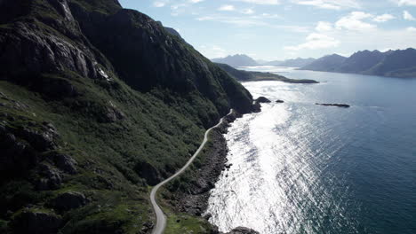 Aerial-dolly-forward-shot-of-a-remote-highway-on-the-edge-of-a-steep-mountain-along-the-rocky-coast-of-northern-Norway-near-the-village-of-Nyksund