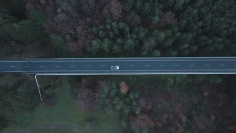 Top-Down-Aerial-View-of-White-Electric-Car-Moving-on-Elevated-Road-in-Twilight,-High-Angle-Drone-Shot
