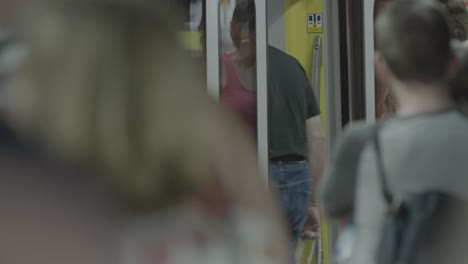 A-crowd-of-diverse-people-wait-for-and-board-a-red-subway-train-in-Stuttgart,-Germany