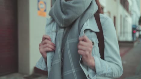 Front-view-of-a-faceless-woman-with-a-scarf-walking-on-the-street-during-a-cold-winter-day