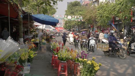 Statische-Aufnahme-Einer-Belebten-Straße-Mit-Mopedfahrern,-Die-An-Einem-Blumenladen-In-Lang-Son-Vorbeifahren