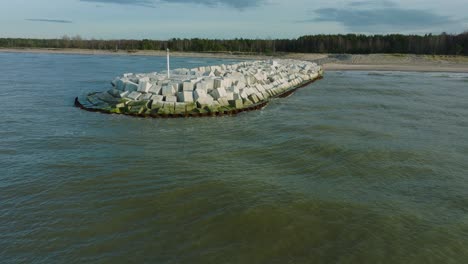 Aerial-establishing-view-of-protective-stone-pier-with-concrete-blocks-and-rocks-at-Baltic-sea-coastline-at-Liepaja,-Latvia,-strengthening-beach-against-coastal-erosion,-drone-shot-moving-forward-low