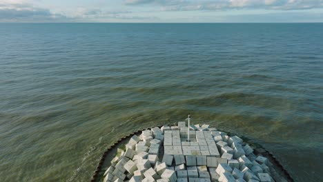 Aerial-establishing-view-of-protective-stone-pier-with-concrete-blocks-and-rocks-at-Baltic-sea-coastline-at-Liepaja,-Latvia,-strengthening-beach-against-coastal-erosion,-low-drone-shot-moving-back