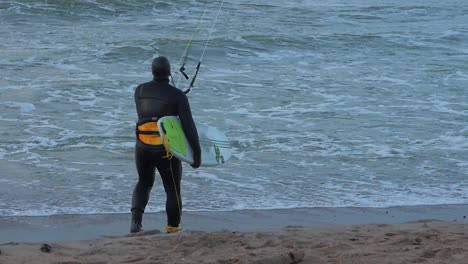 Mann-Beim-Kitesurfen,-Bewölkter-Wintertag,-Hohe-Wellen,-Ostsee-Karosta-Strand,-Zeitlupe,-Mittlere-Aufnahme