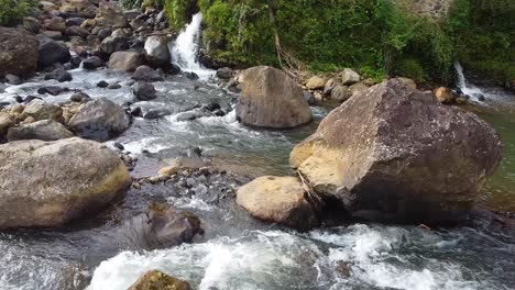 drone-shot,-water-flowing-on-the-rocks-in-the-middle-of-the-river