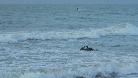 Man-engaged-in-kitesurfing,-overcast-winter-day,-high-waves,-Baltic-Sea-Karosta-beach-,-slow-motion,-medium-shot