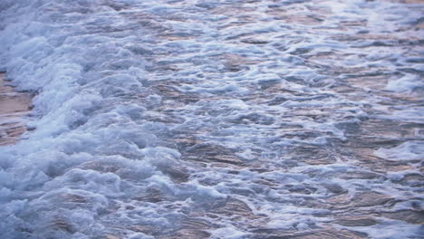 Beunruhigendes-Meerwasser-Reflektiert-Rosafarbenes-Sonnenlicht,-Während-Eine-Schäumende-Welle-überspült-Wird
