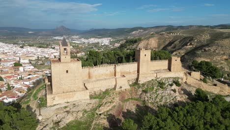 Fortaleza-De-Antequera-Y-Ondeando-La-Bandera-Española-En-Andalucía,-España---Tiro-Circular-Aéreo-De-4k