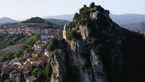 Left-orbiting-reveal-shot-of-Bagnoli-del-Trigno-town-with-San-Silvestro-church-between-two-rock-spurs,-Isernia-and-Molise-region,-Italy,-4K