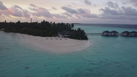 Aerial-drone-reveal-shot-of-a-small-island-in-the-Maldives-at-sunrise