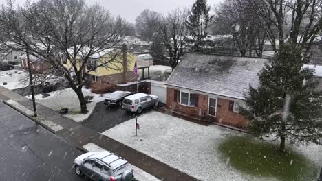 American-flag-waving-beside-house-in-USA-during-winter-snowstorm