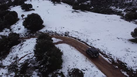 Camión-De-Vehículos-4x4-En-Una-Montaña-De-Camino-De-Tierra-Cubierta-De-Nieve-Blanca,-Antena