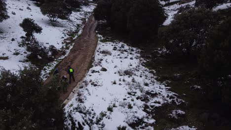 Group-of-people-with-children-enjoying-outdoor-snow-time,-walking-on-dirt-road