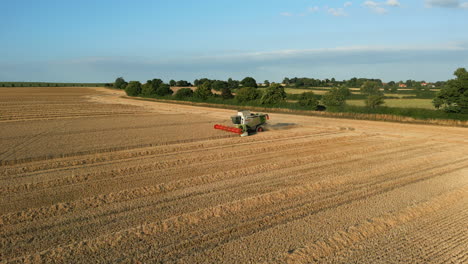 Low-Drone-Shot-of-Claas-Combine-Harvester-Harvesting-with-Tractor-Coming-Around-at-Golden-Hour-UK