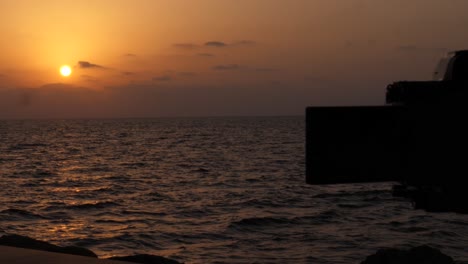 Silhouette-Des-Ausklappbaren-Bildschirms-Und-Der-DSLR-Kamera,-Die-Den-Orangefarbenen-Sonnenuntergang-über-Dem-Ozean-Filmen