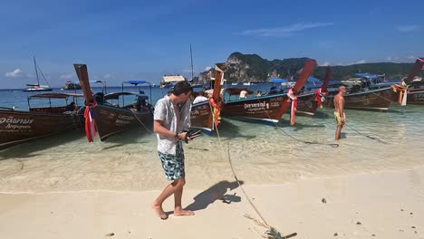 Pov-Caminando-Más-Allá-De-La-Fila-De-Botes-Tradicionales-De-Cola-Larga-Al-Lado-De-La-Playa-En-Phi-Phi,-Tailandia