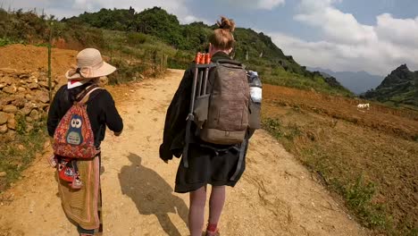 POV-Hyper-lapse-Walking-Behind-Guide-And-Female-Tourist-Along-Rural-Path-In-Sapa,-Vietnam